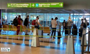 Fluggäste mit Masken beim Check-Inn am Dortmunder Flughafen