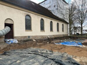 Unter den Planen liegen die außerhalb der Kirche entdeckten Gräber.